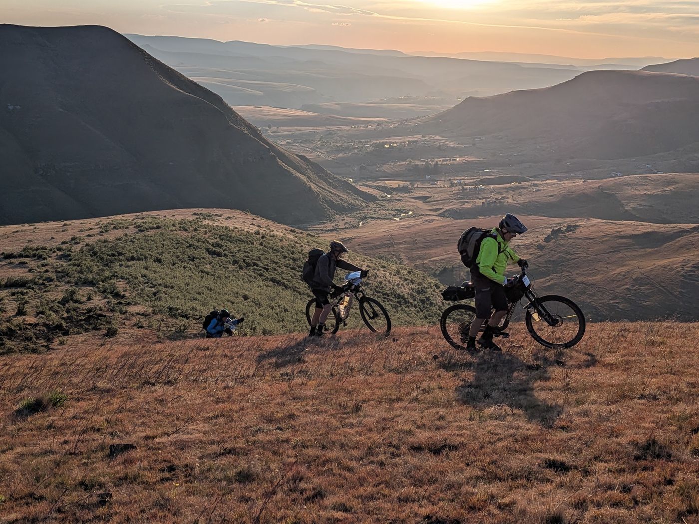 Riders pushing up a grassy ridge at sunrise, Freedom Challenge 2026